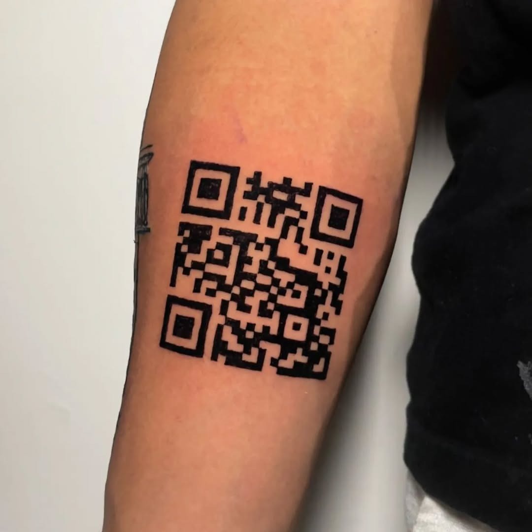 This tattoo features a bold, black barcode design etched onto the forearm.