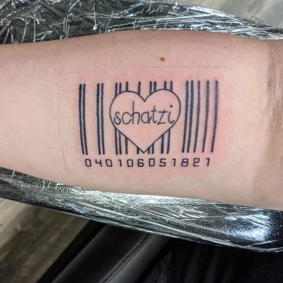 This tattoo features a stylized barcode with a heart in the center, highlighting the word 'schatzi.' The combination creates a personal and affectionate vibe, perfect for representing love or special connections.