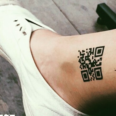This tattoo features a bold QR code resting on the ankle, making a striking statement.