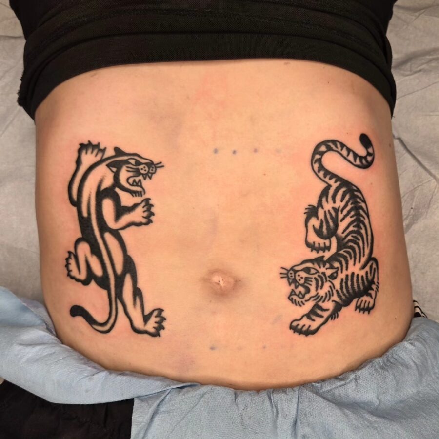 This image features two dynamic tattoos on a belly, showing a fierce tiger and a powerful panther.