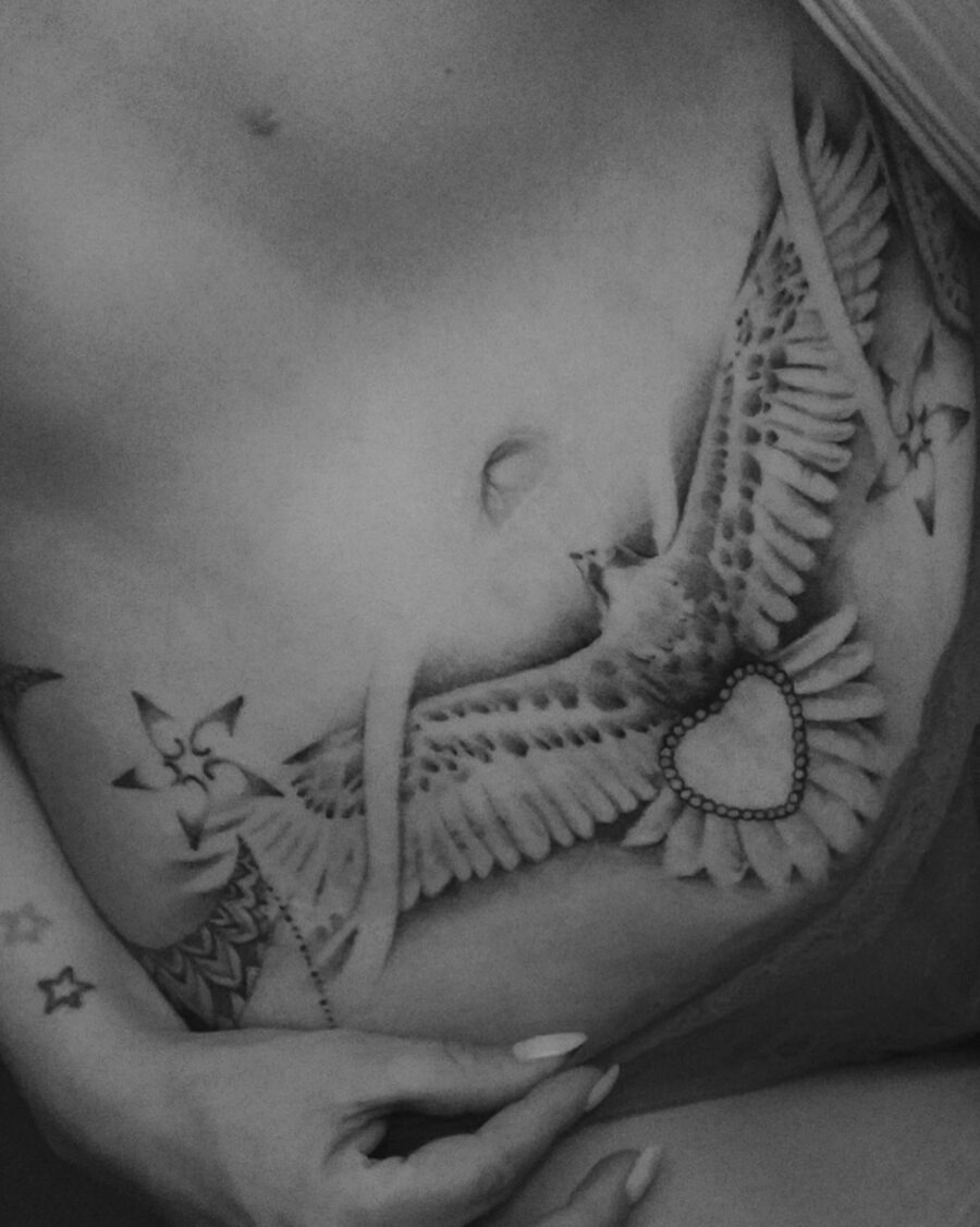 This stunning belly tattoo features a beautifully detailed bird with intricate feather patterns.