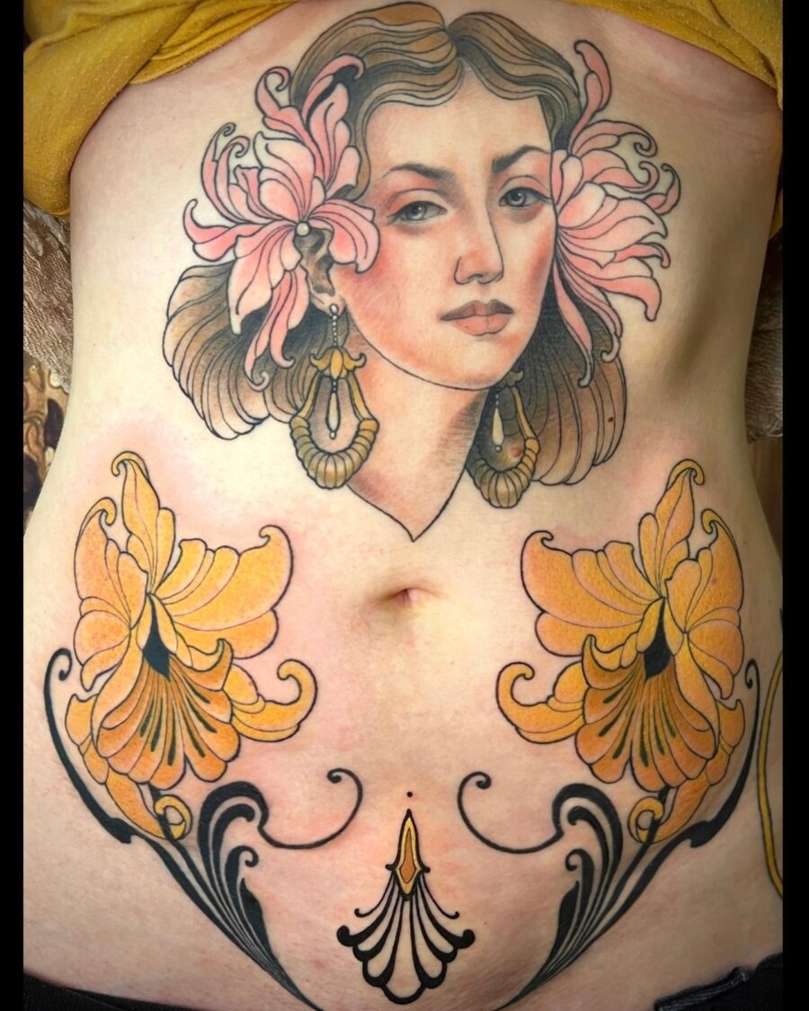 This stunning belly tattoo showcases a beautifully crafted female portrait surrounded by floral designs.