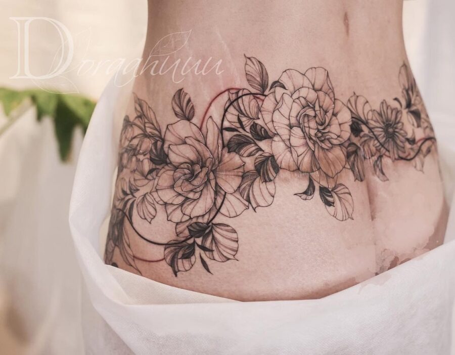 This belly tattoo features a stunning arrangement of delicate flowers and leaves.