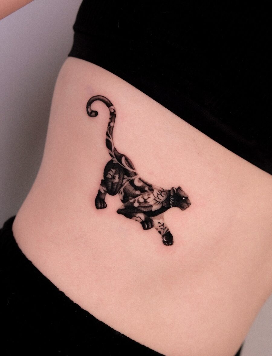 Showing a stunning belly tattoo of a leaping tiger, this design beautifully combines strength with floral elements.