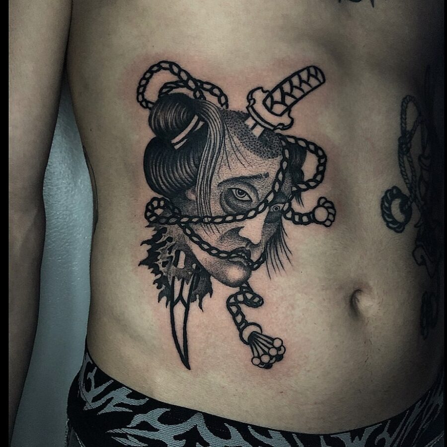 This bold belly tattoo showcases a detailed design of a woman entwined in chains, set against a stark black ink backdrop.