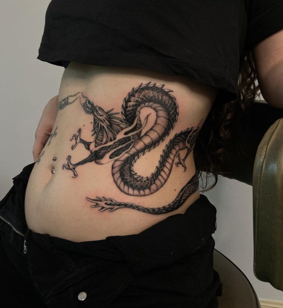 This striking belly tattoo features a detailed dragon, elegantly coiling around the waist.