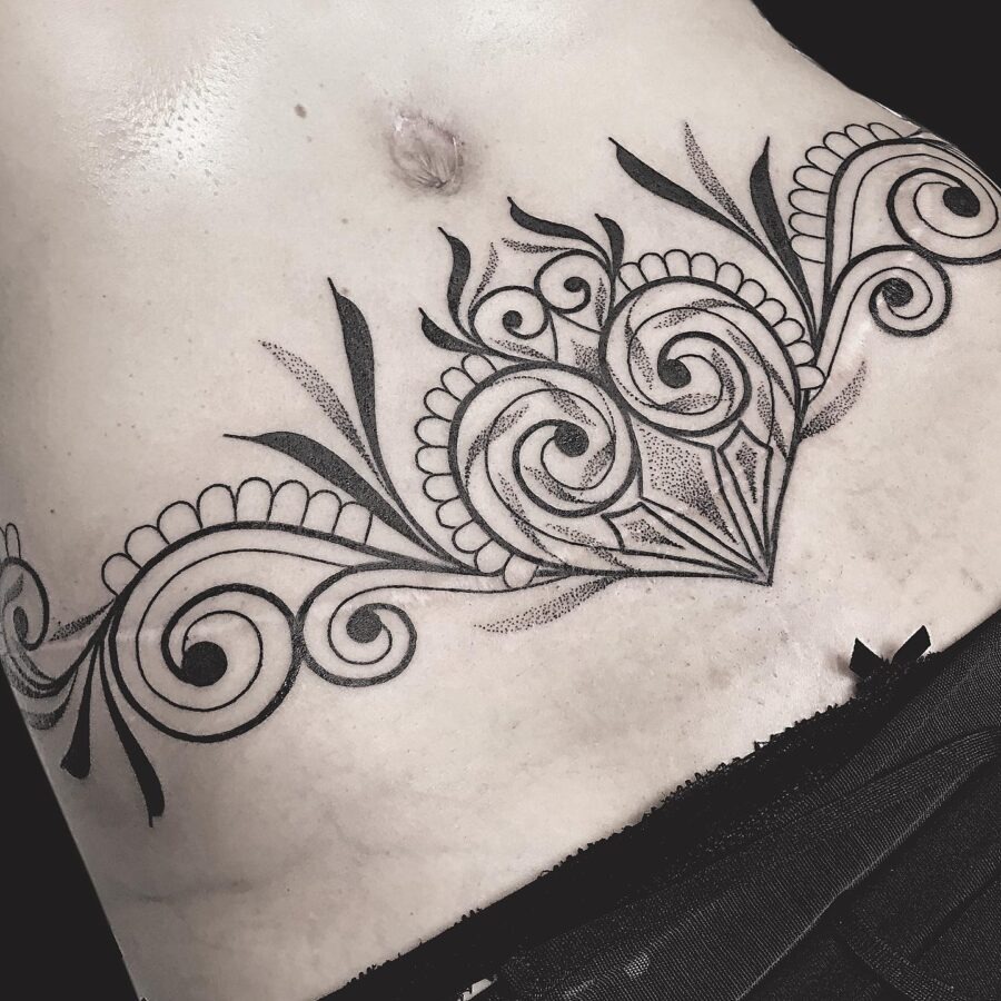 This belly tattoo features an ornate floral pattern that beautifully outlines the midsection.