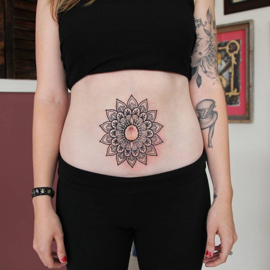 This stunning belly tattoo features a detailed mandala design that captivates the eye.