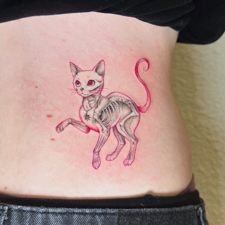 This belly tattoo features a whimsical cat illustrated with a skeletal structure, combining cute and edgy vibes.