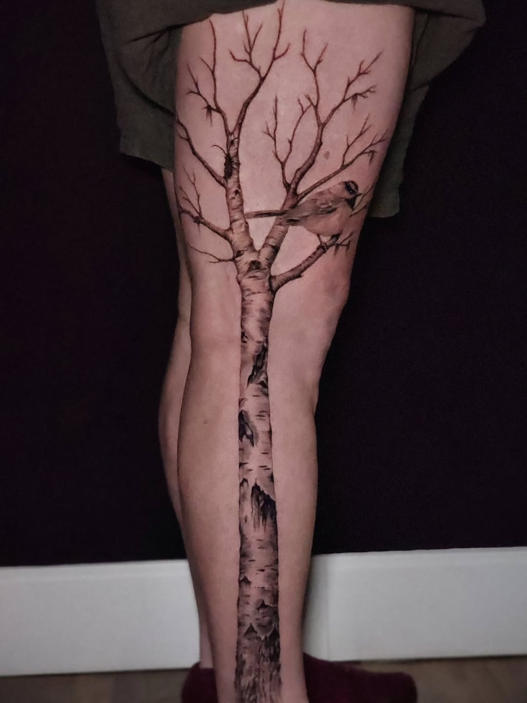 This tattoo beautifully captures the essence of a birch tree, extending organically along the leg.