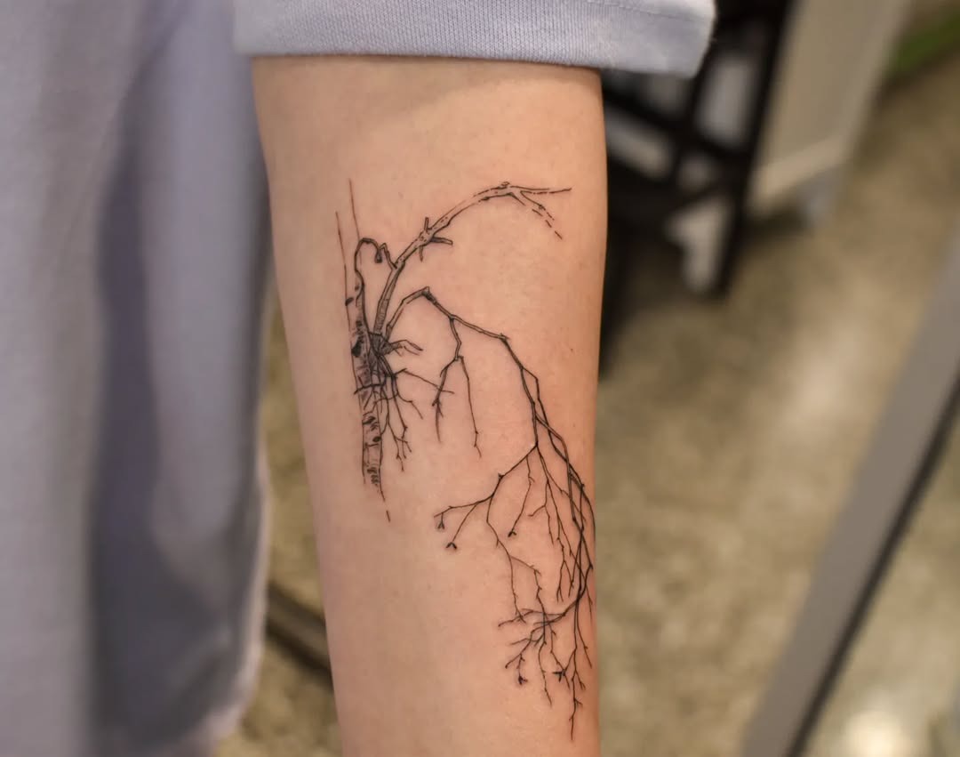 This tattoo showcases a striking depiction of birch tree roots extending elegantly along the skin.