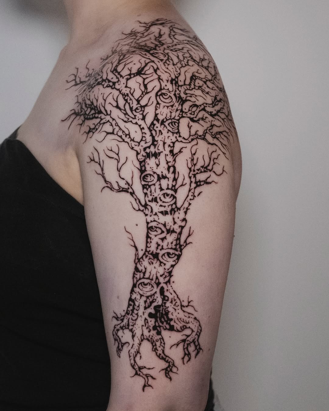 This tattoo showcases a striking birch tree design covering the upper arm.