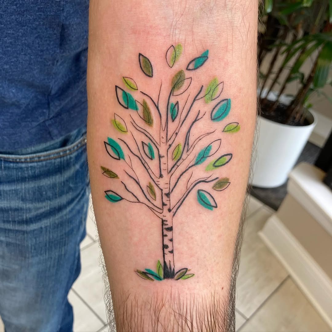 This birch tree tattoo features an intricate design with lively green and blue leaves.