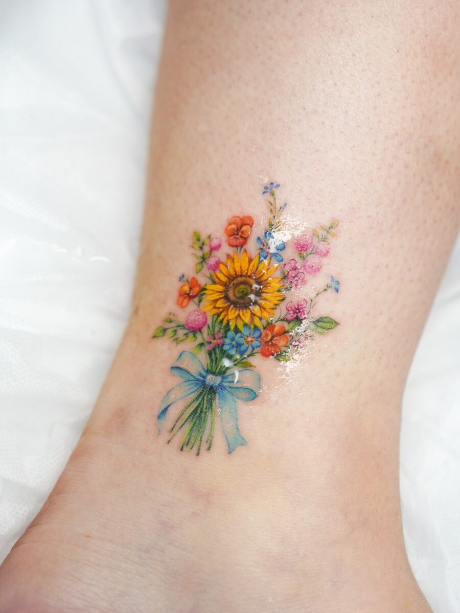 This tattoo features a beautiful bouquet of sunflowers and assorted flowers.