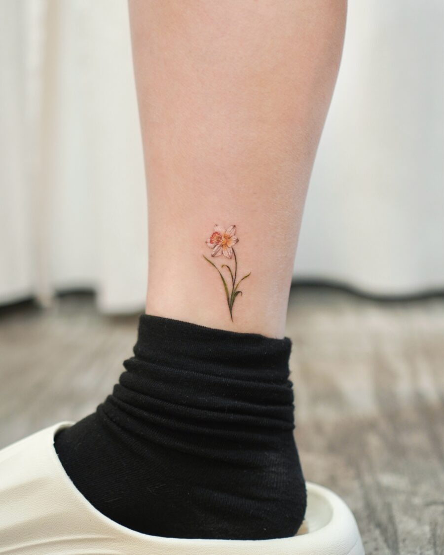 This tattoo features a delicate flower, elegantly positioned on the ankle.