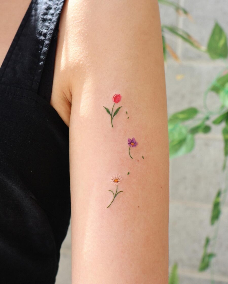 This tattoo features a delicate arrangement of flowers on the arm.