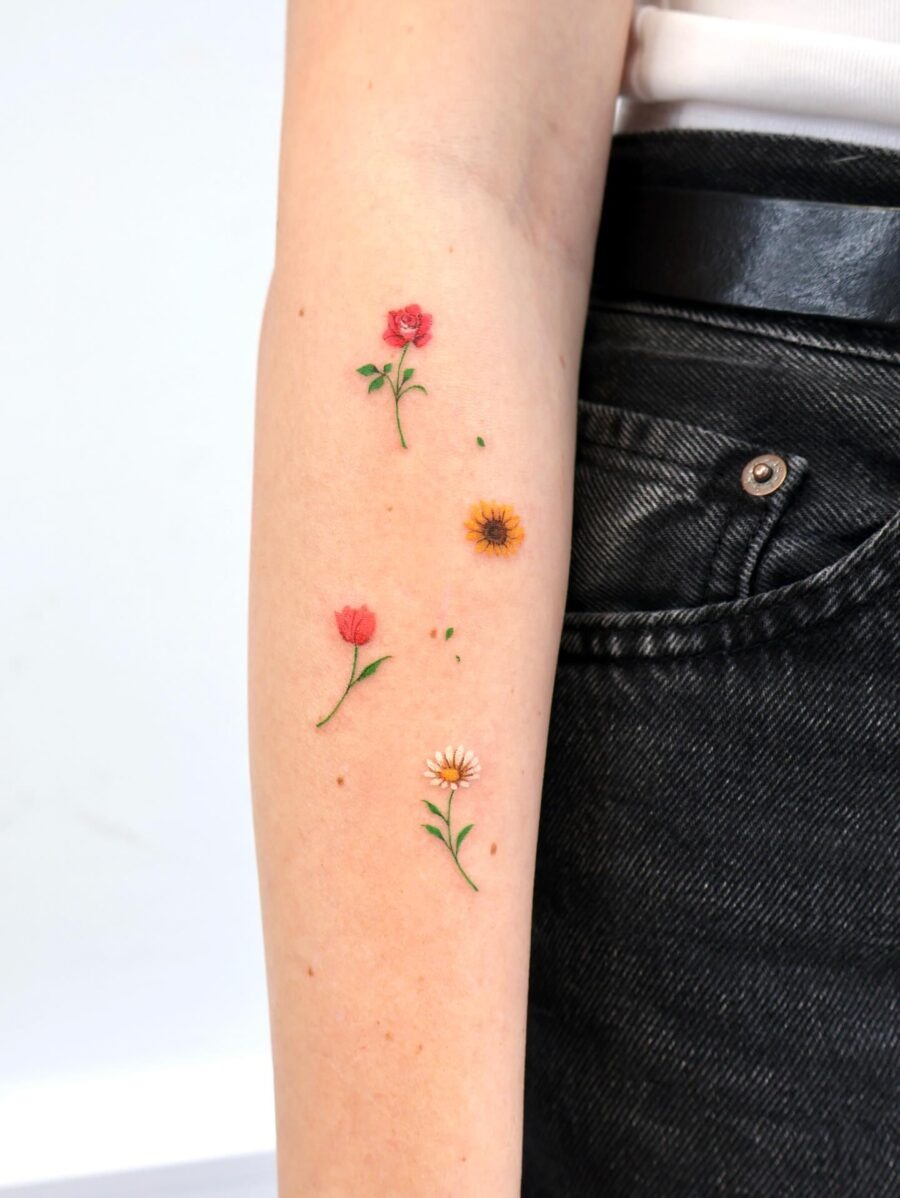 This striking tattoo design features delicate flowers, including a rose, sunflower, and daisy, on a person's arm.