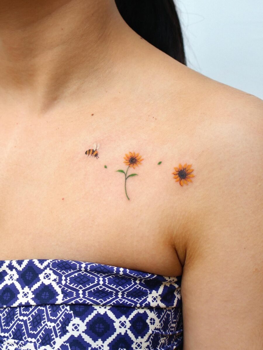 This tattoo features a delicate stem with vivid orange flowers accompanied by a small buzzing bee.