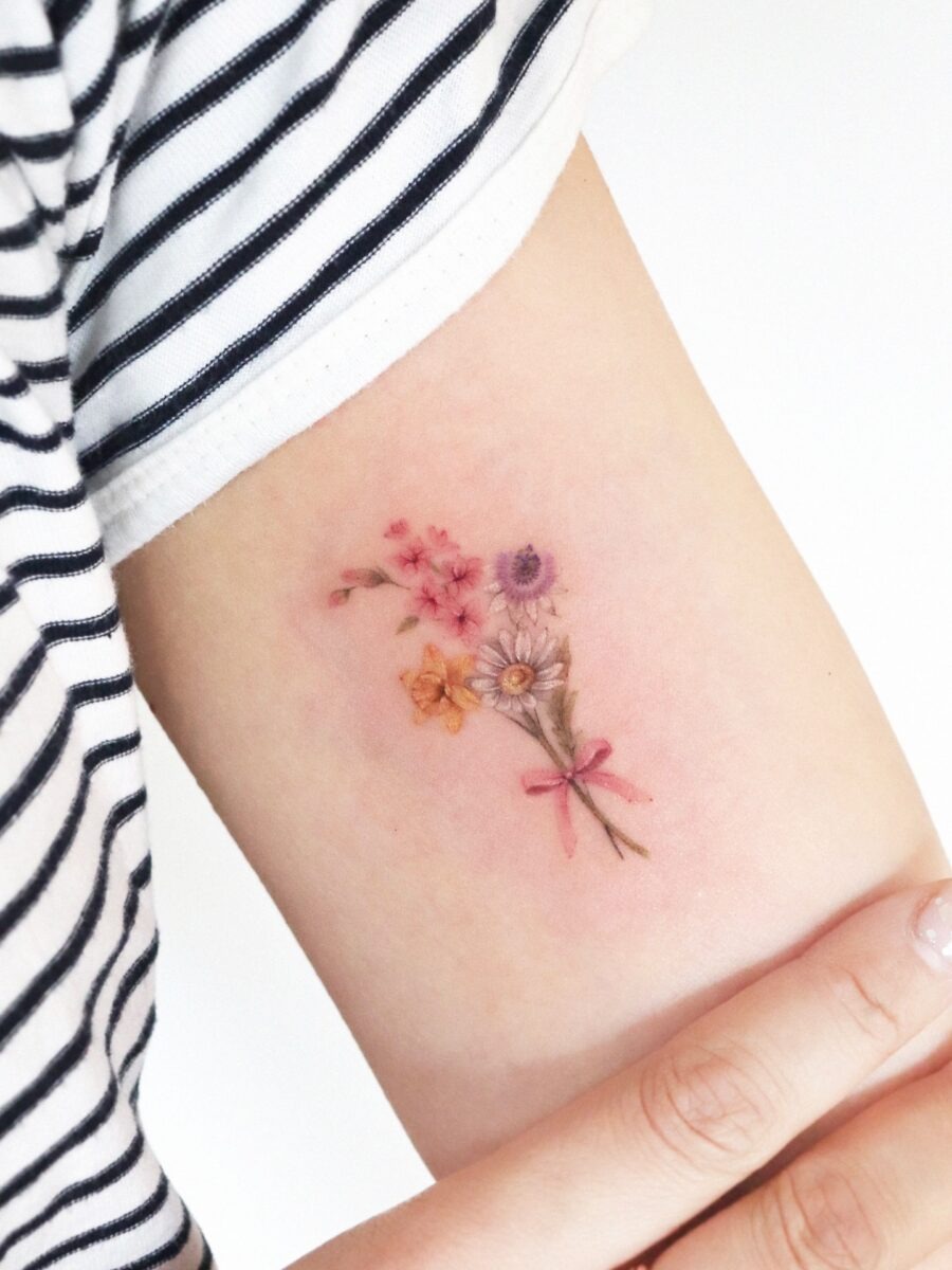 This tattoo features a delicate arrangement of colorful birth flowers, evoking a sense of joy and vibrancy.