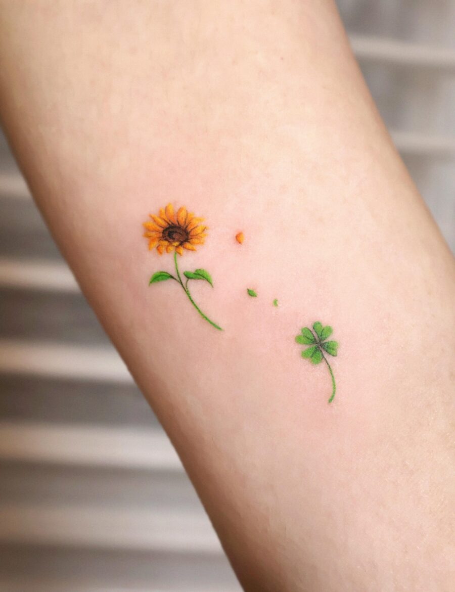 This delightful tattoo features a sunflower alongside a clover, symbolizing joy and good luck.