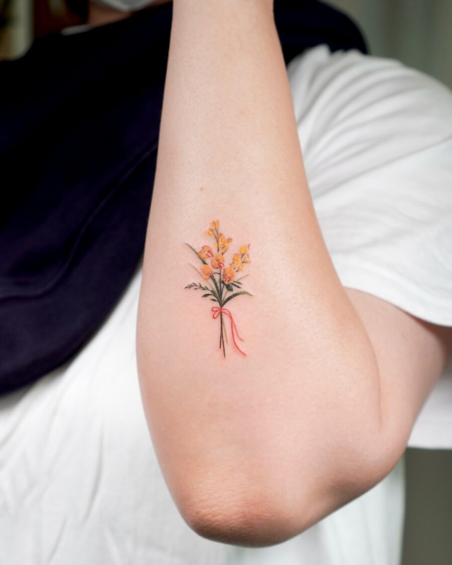This tattoo features a beautiful arrangement of flowers in hues, showing artistry and elegance.