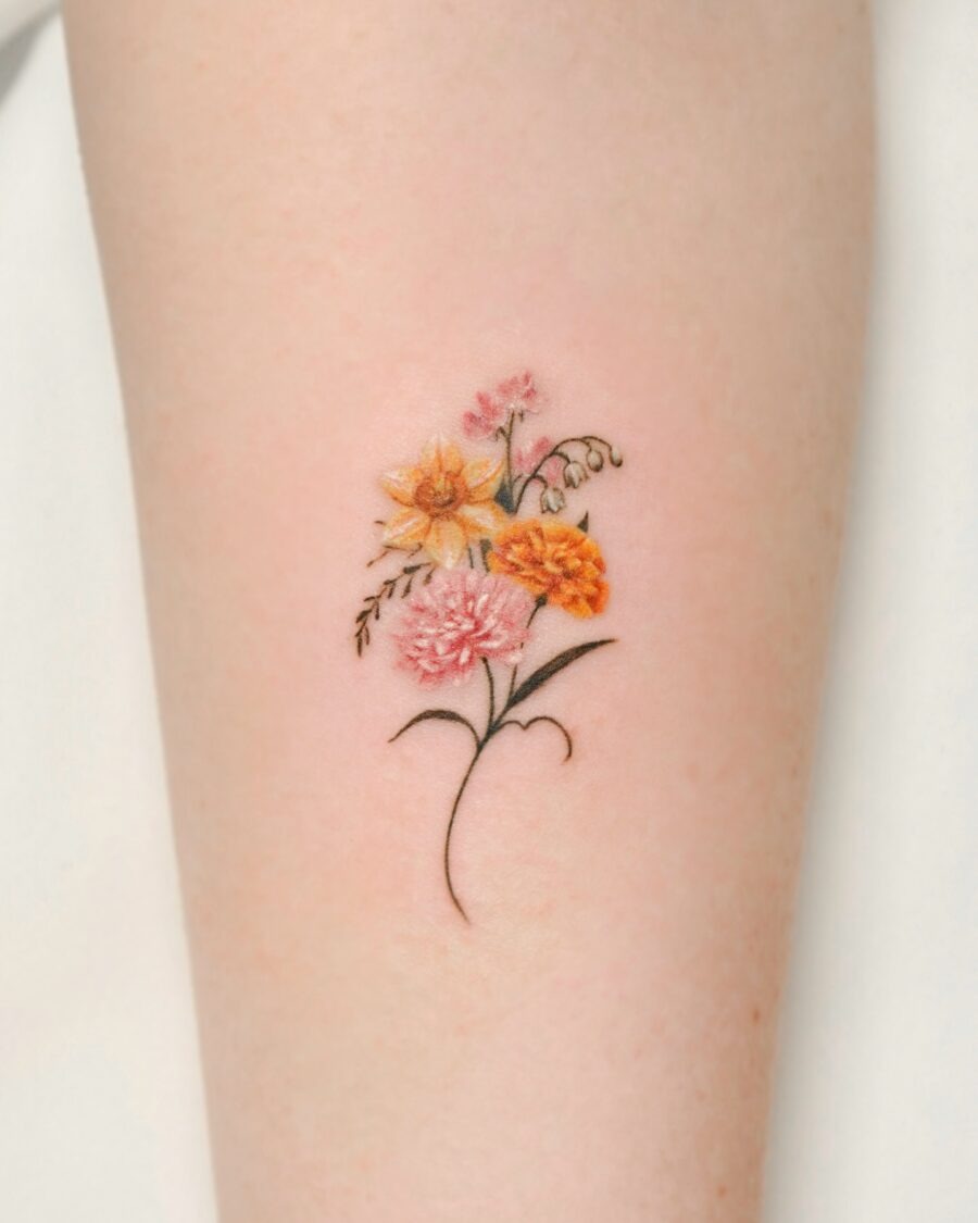 This tattoo showcases an arrangement of various flowers, including rich yellows, soft pinks, and earthy tones.