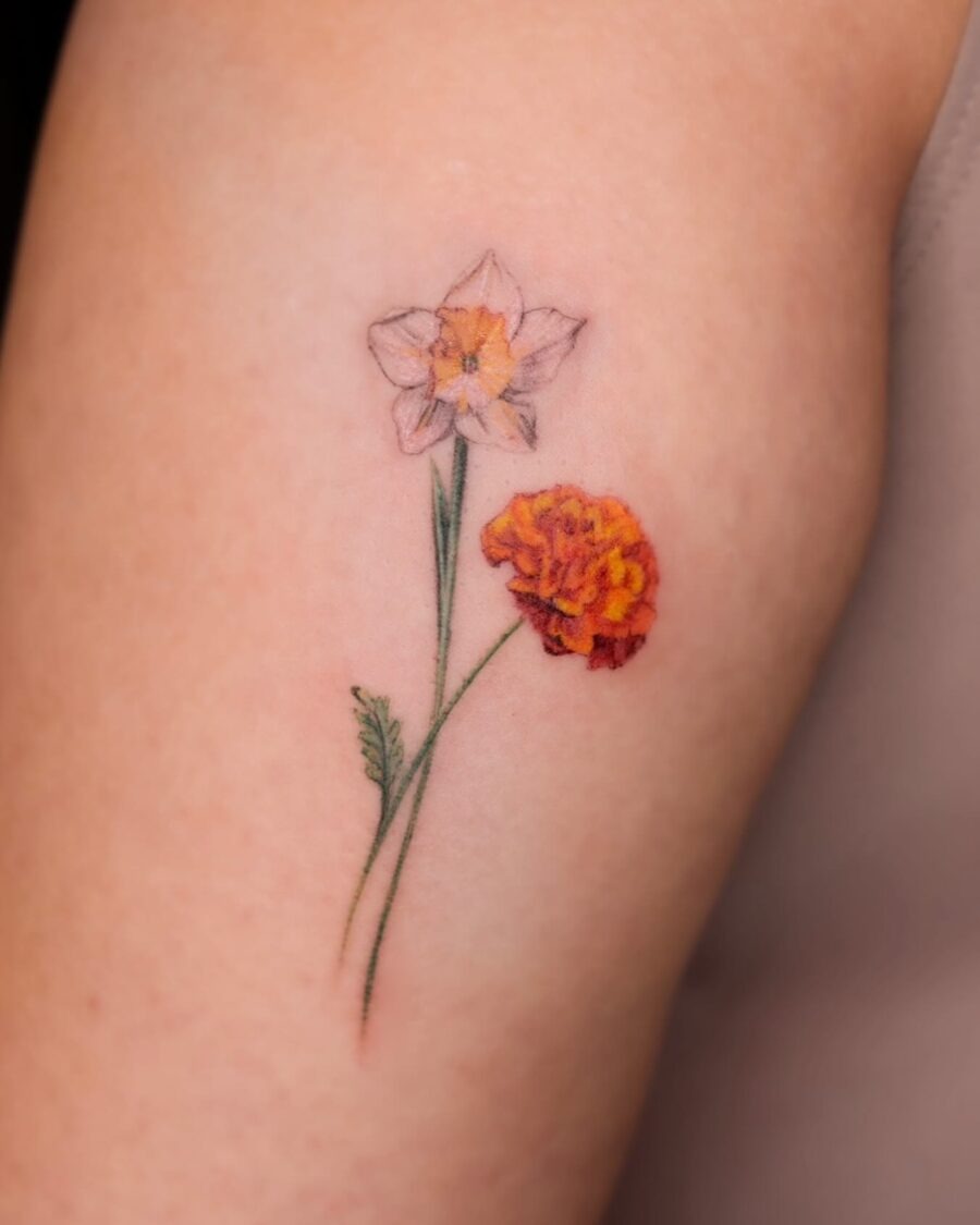 This tattoo showcases a delicate daffodil alongside a marigold.