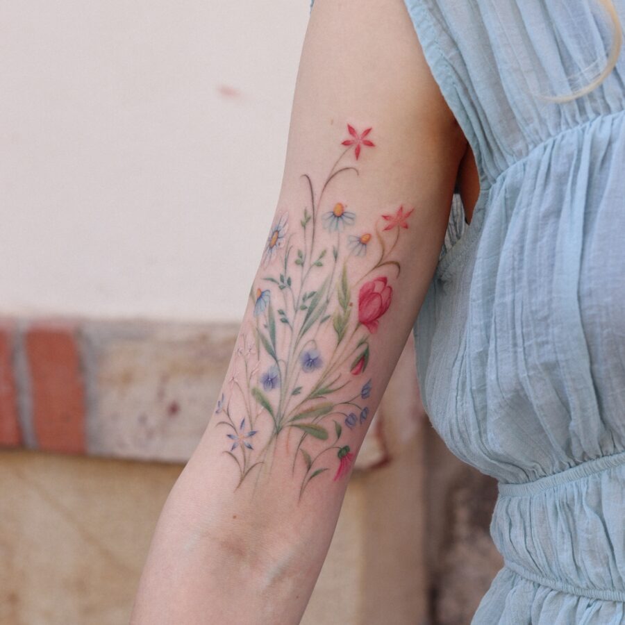 This tattoo features a beautiful array of flowers, showing a mix of delicate blooms.