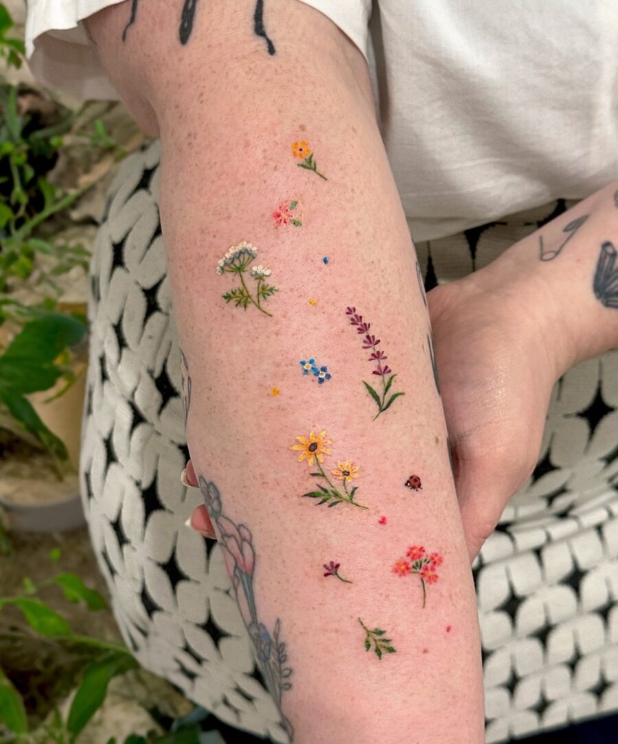 This arm tattoo features an array of delicate flowers, each representing a different birth month.