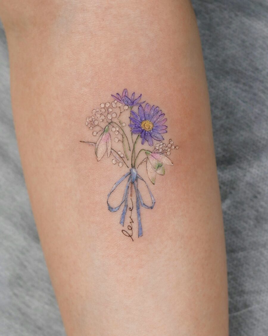 This beautiful tattoo features a bouquet of daisies adorned with a sweet blue ribbon.
