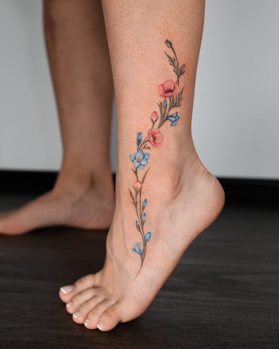 This tattoo features a graceful array of colorful flowers, gracefully winding along the ankle.