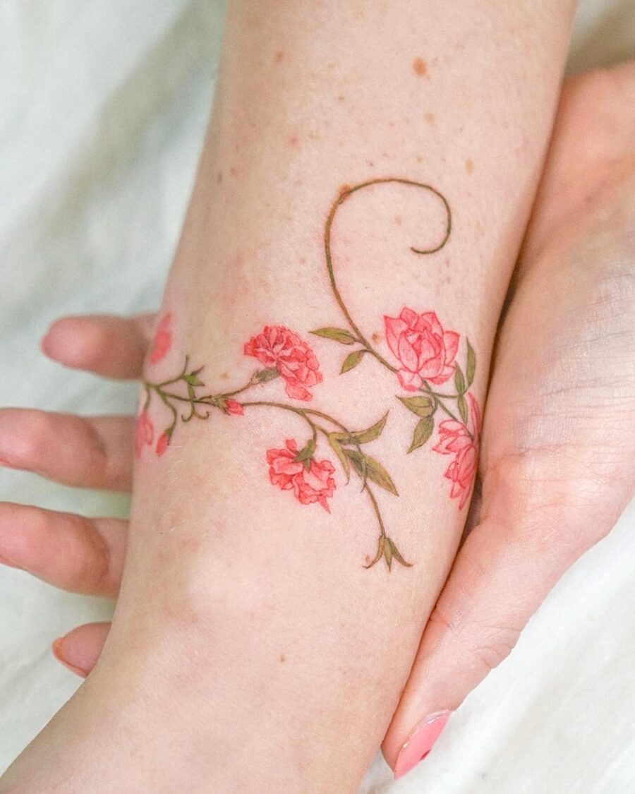 This beautiful tattoo features delicate pink flowers entwined with slender green stems.