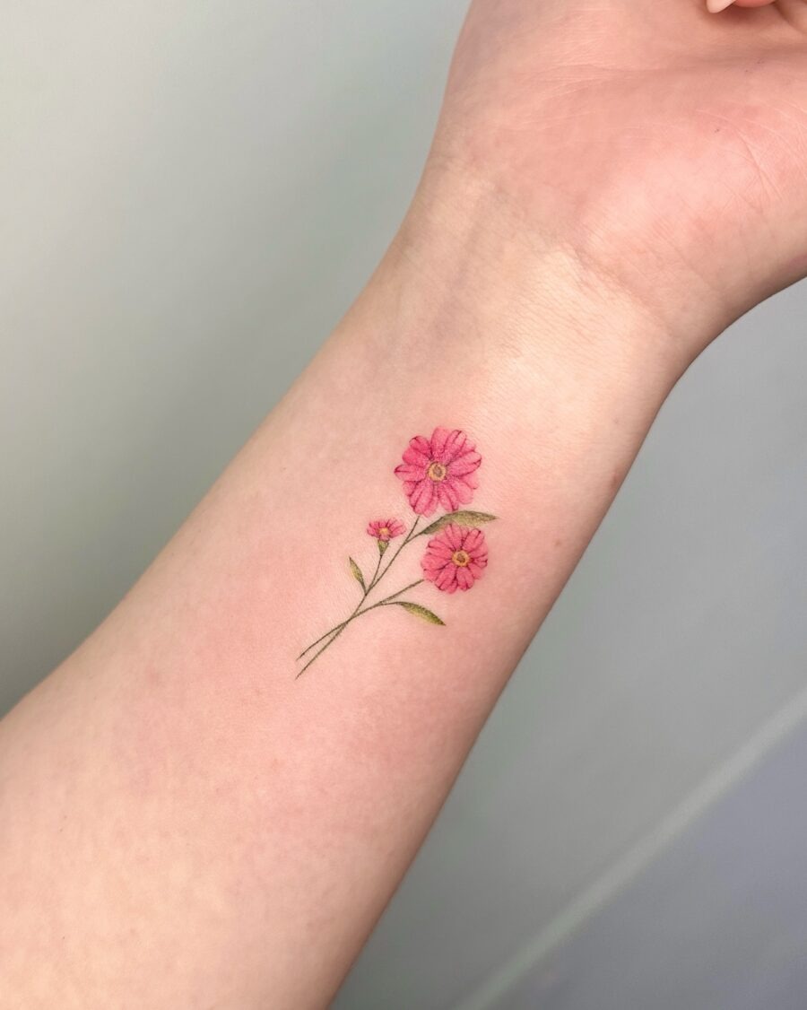 This charming pink flower tattoo unfolds gently on the arm, showing its intricate details.