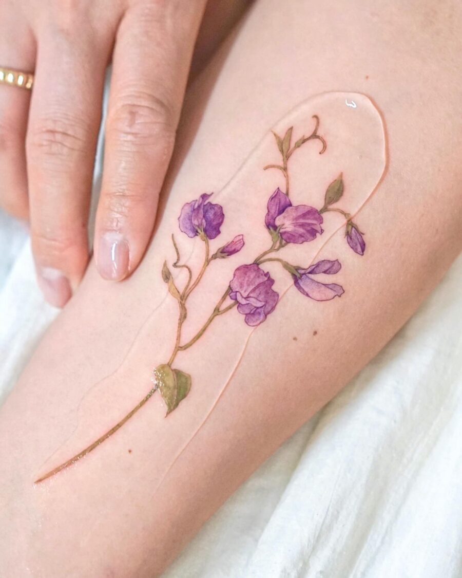 This tattoo features a stunning design of purple flowers delicately inked on a person's arm.