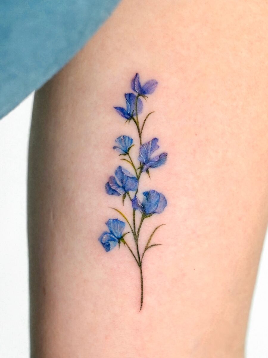 This tattoo features delicate blue flowers gracefully climbing up the skin.