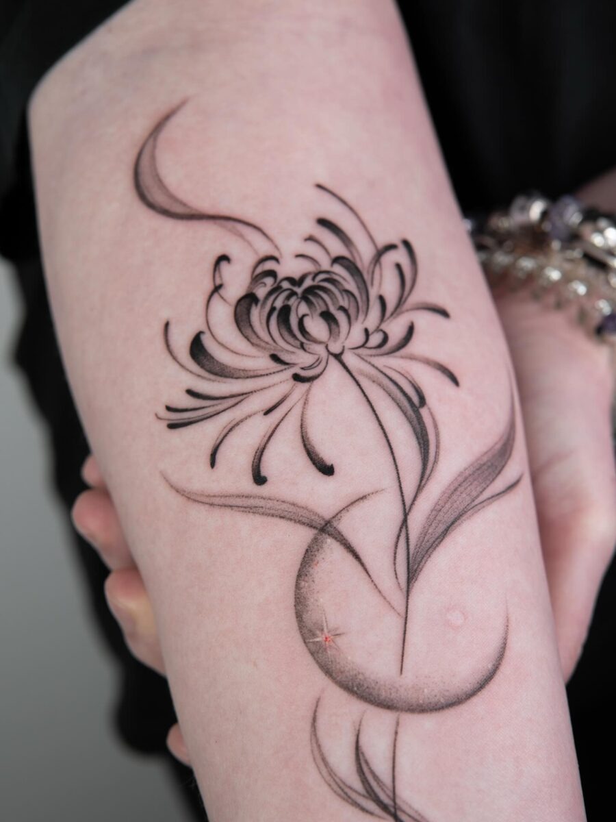 This tattoo features an intricate chrysanthemum, symbolizing optimism and joy.