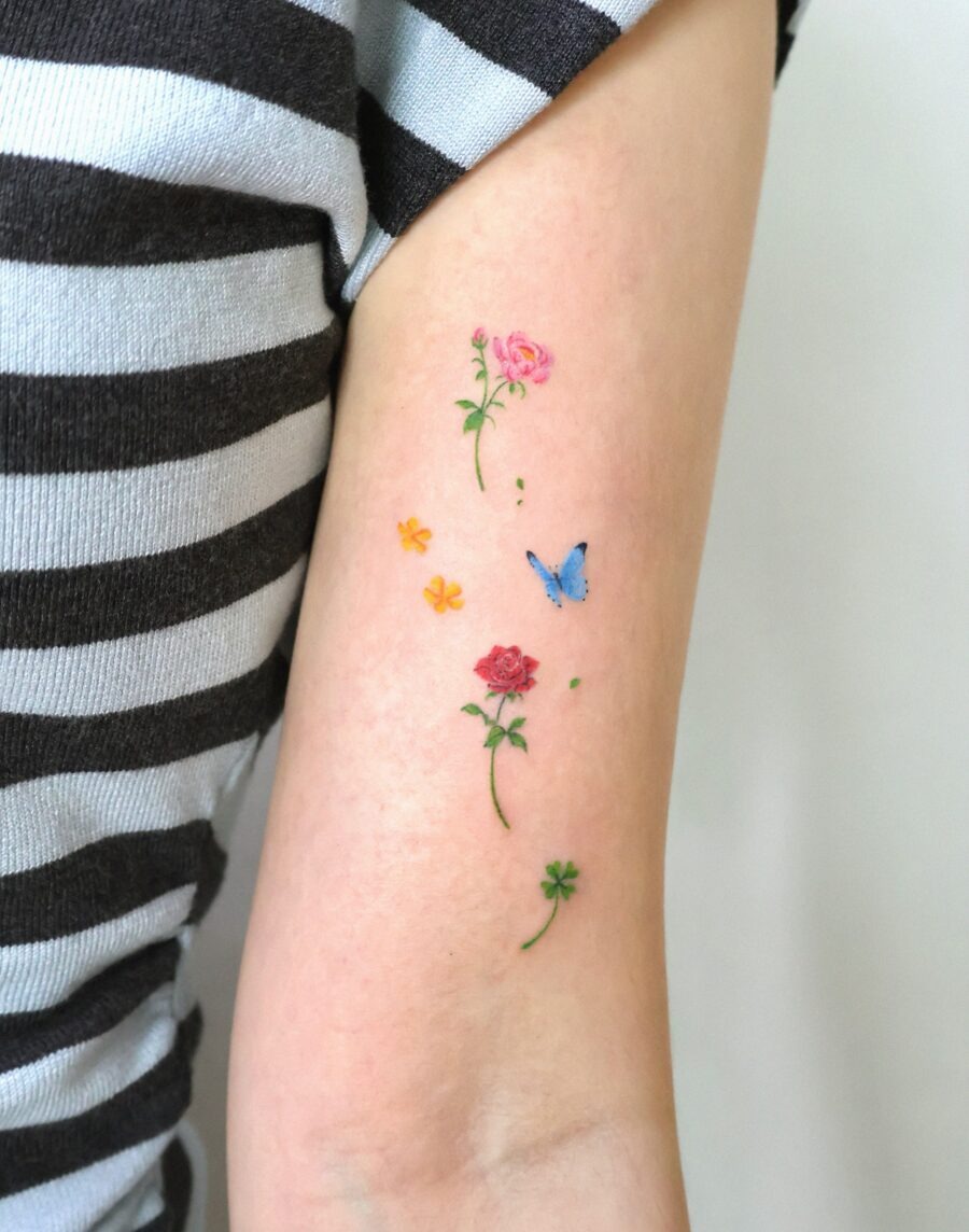 This tattoo features a delicate arrangement of flowers with a touch of blue butterfly.
