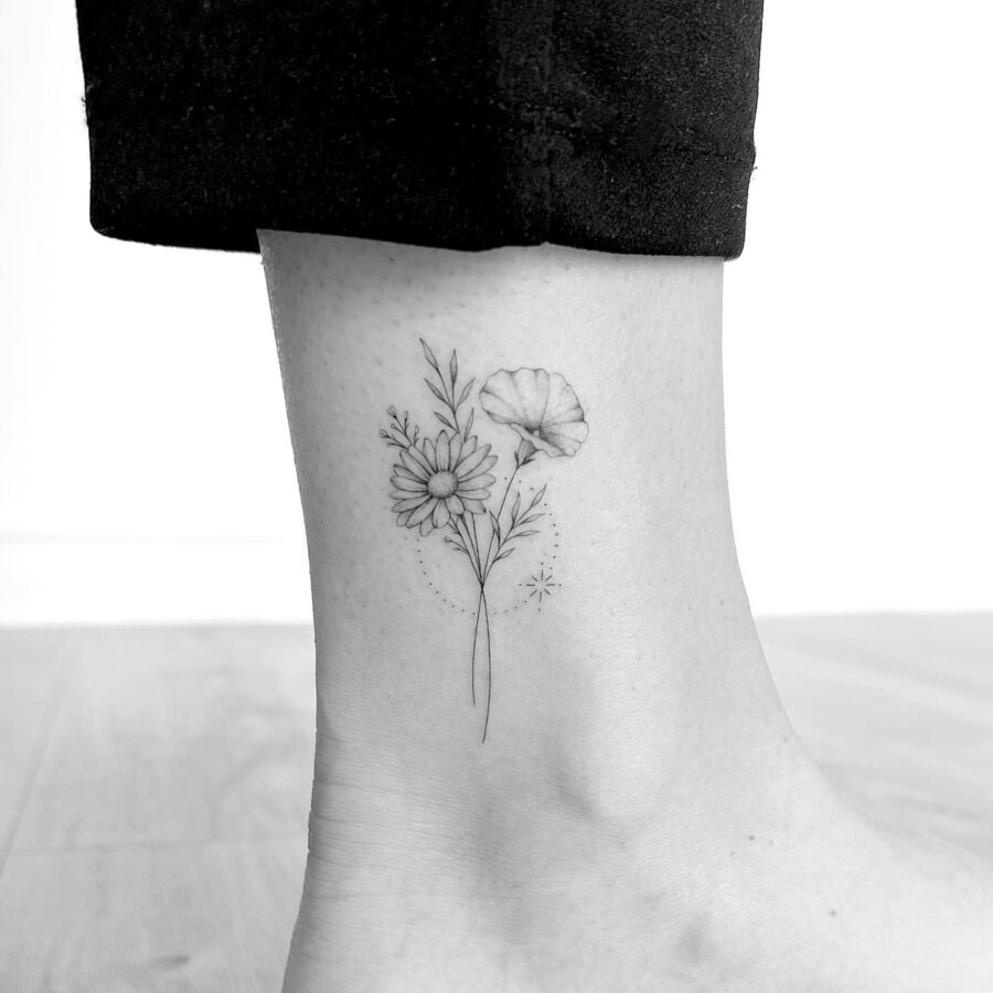 This ankle tattoo features delicate flowers with fine line work, presenting an elegant touch to the skin.