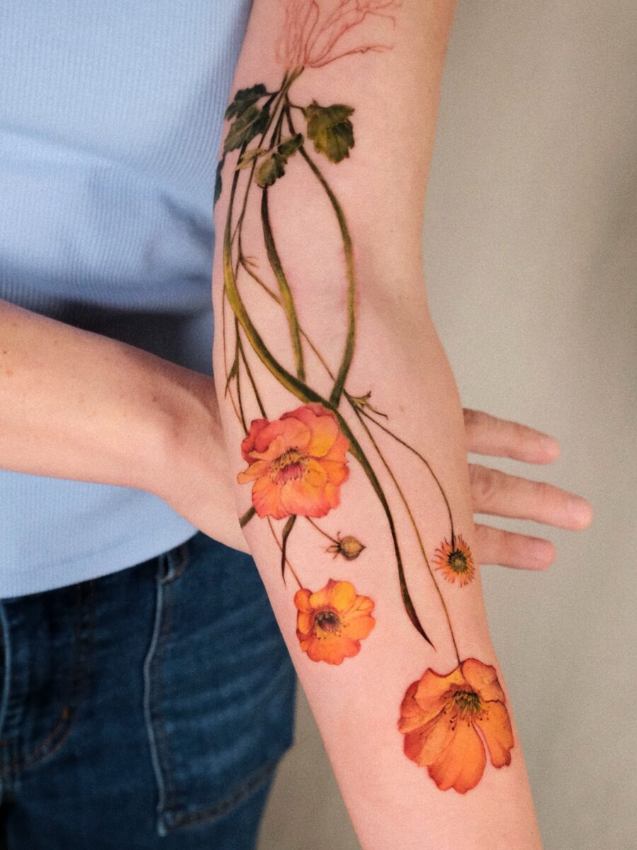 This stunning birth flower tattoo features beautifully rendered blossoms that stretch elegantly along the forearm.