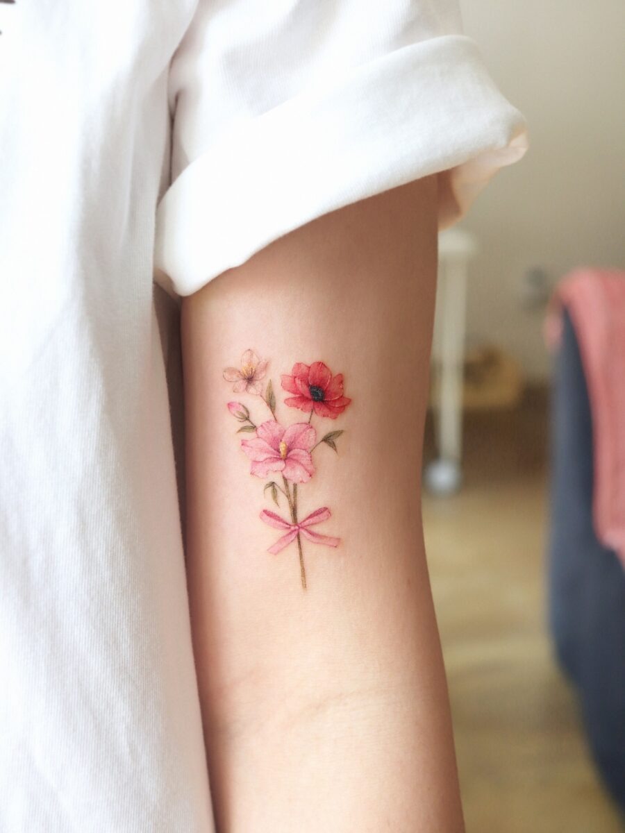 This tattoo features beautifully designed pink flowers with a charming bow, embodying a sense of elegance and femininity.