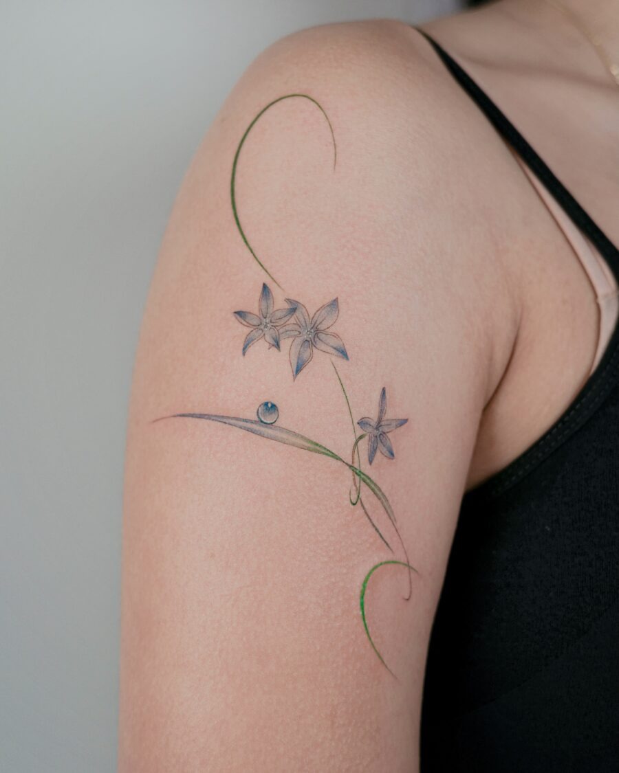 This delicate flower tattoo gracefully adorns the shoulder, blending artistry with nature.