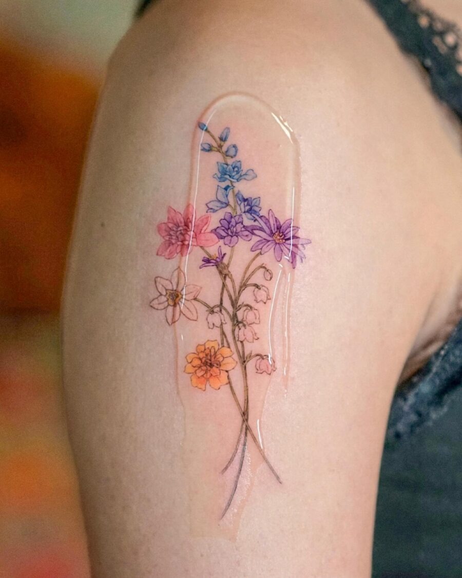 This tattoo showcases an array of flowers beautifully illustrated in soft watercolor.