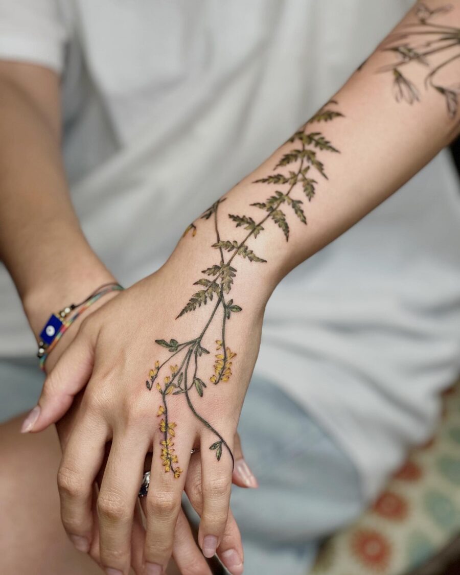 This stunning birth flower tattoo features delicate floral elements elegantly wrapped around the forearm.
