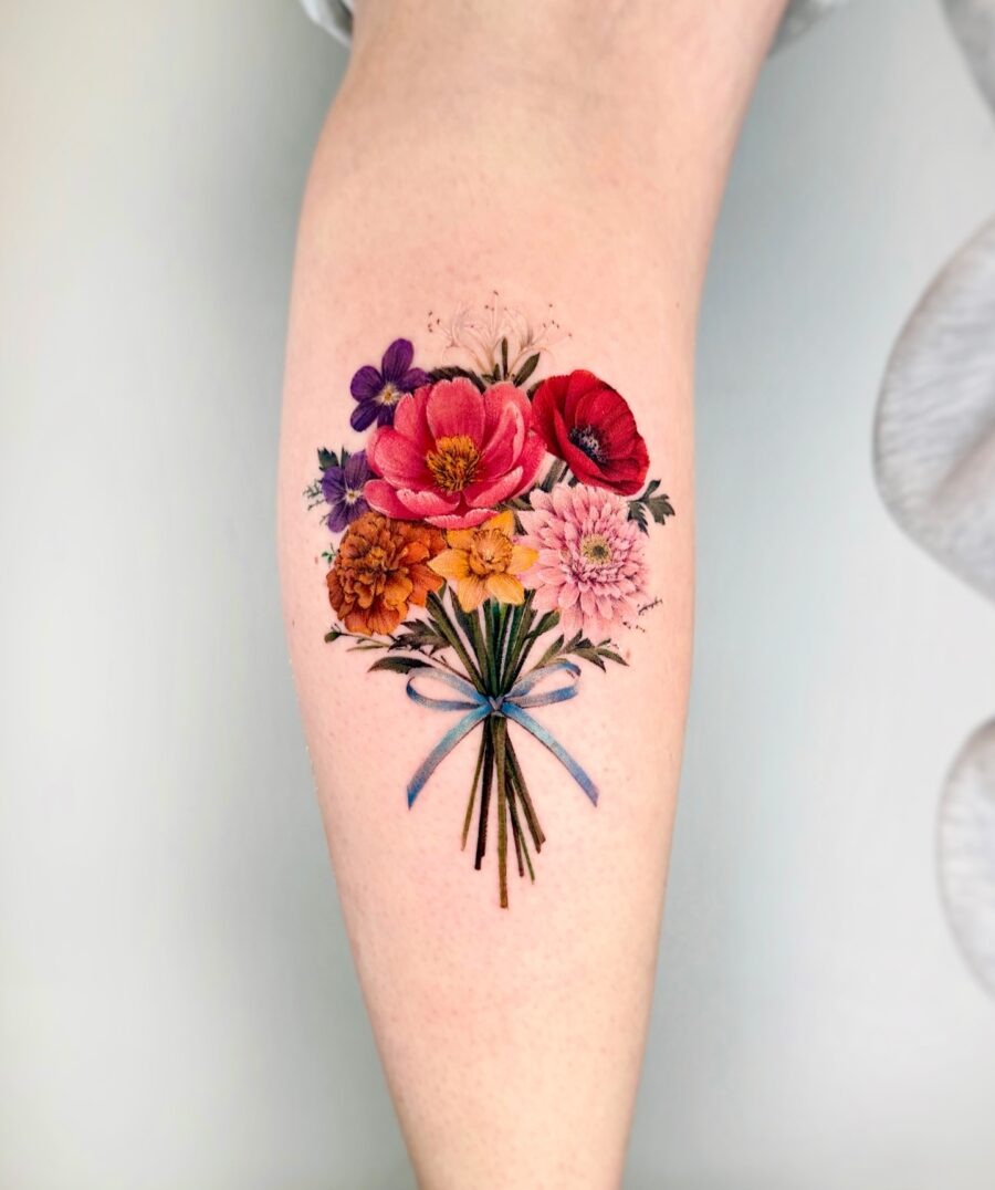 This tattoo showcases a beautiful bouquet of colorful flowers, including pinks, yellows, and purples.