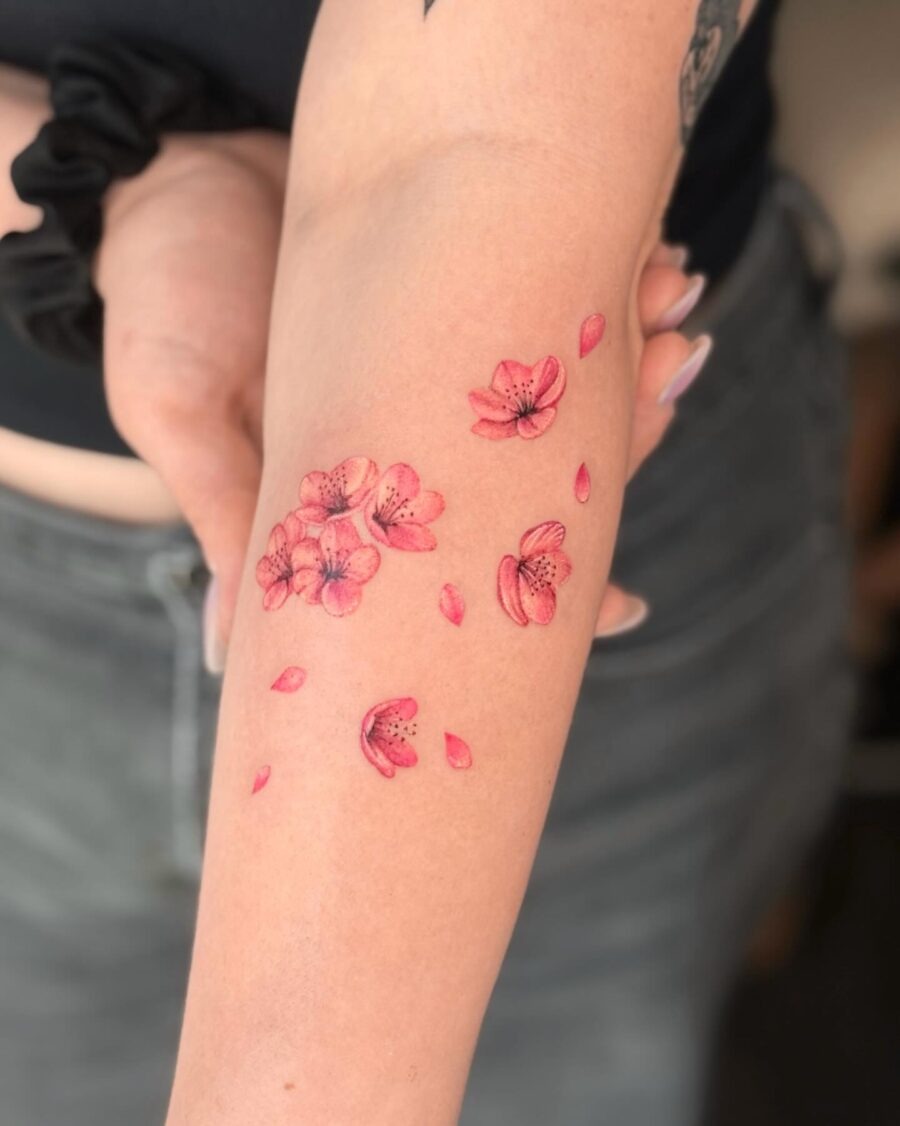 This tattoo features delicate cherry blossoms in varying shades of pink, creating a soft and feminine vibe.