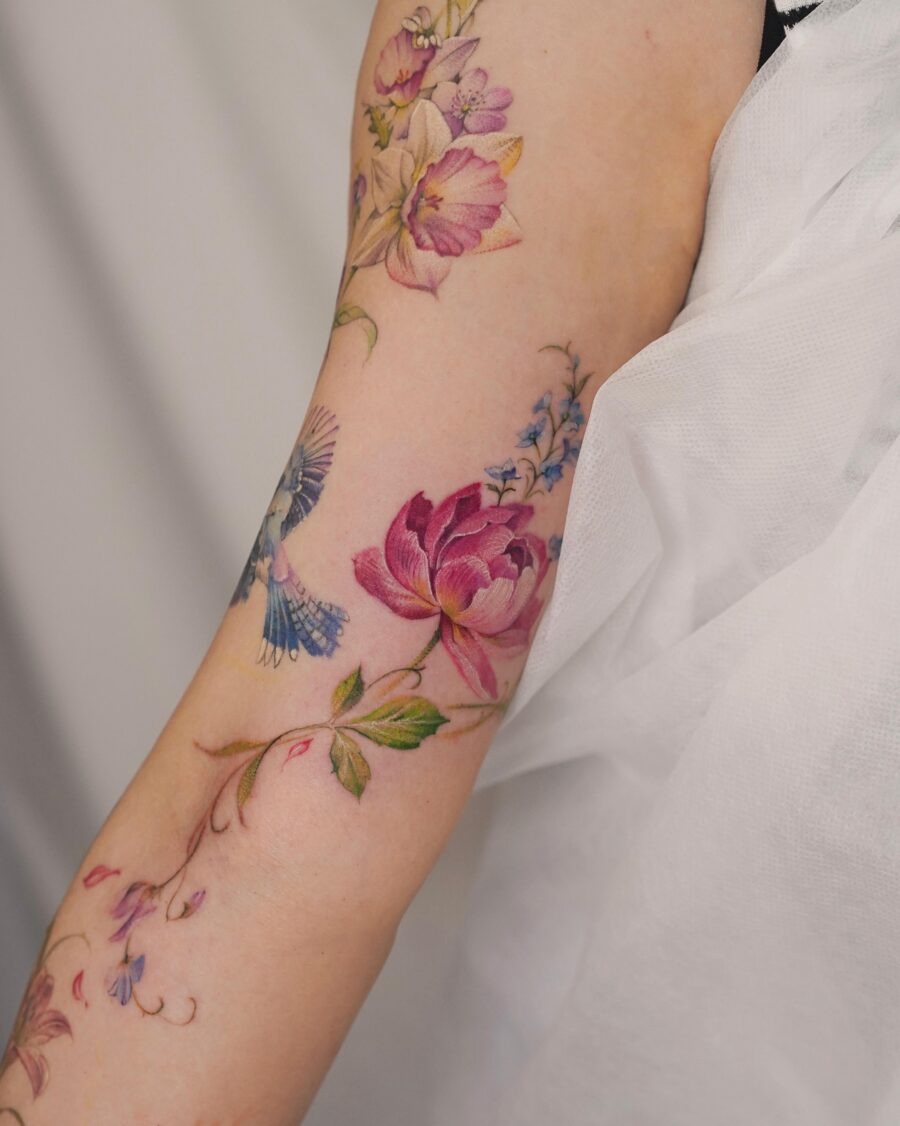 This stunning tattoo features a blend of colorful flowers, creating a lively and enchanting aura.