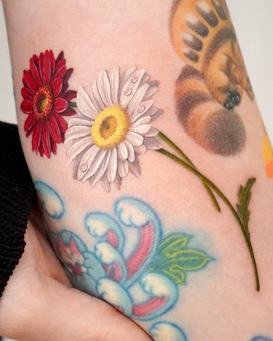 This tattoo features a striking combination of red and white flowers, showing the beauty of nature on skin.