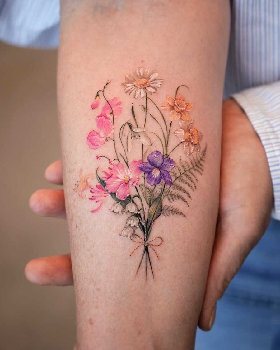 This stunning tattoo showcases a colorful bouquet of various flowers, intertwining beauty with personal significance.