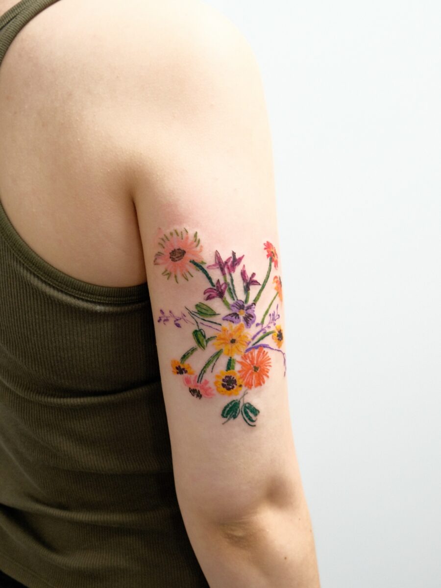 This stunning birth flower tattoo showcases a delightful array of blooms on the upper arm.