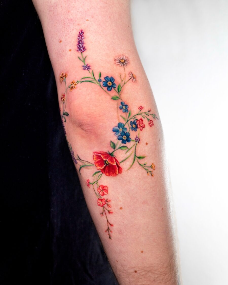 This stunning tattoo features an array of colorful flowers spiraling elegantly around the arm.